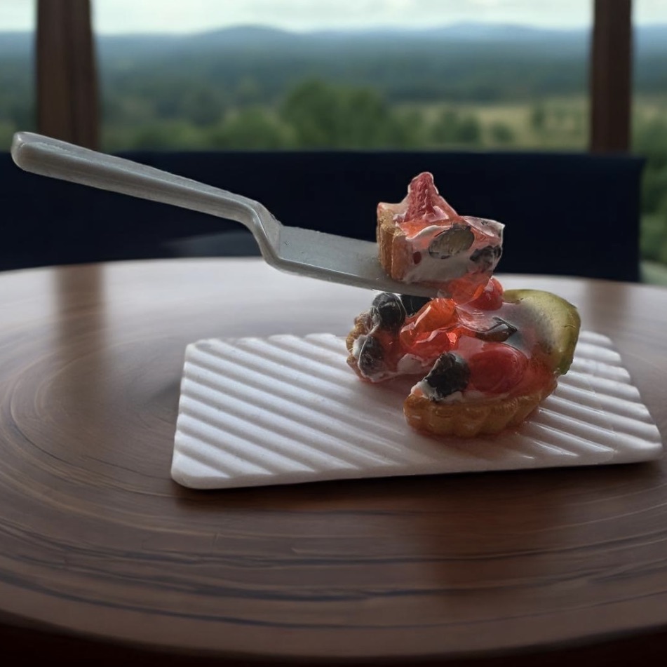 a closeup picture of a spatula removing a slice from a fruit tart